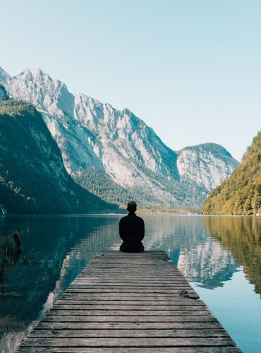 a person sitting on a dock overlooking a lake